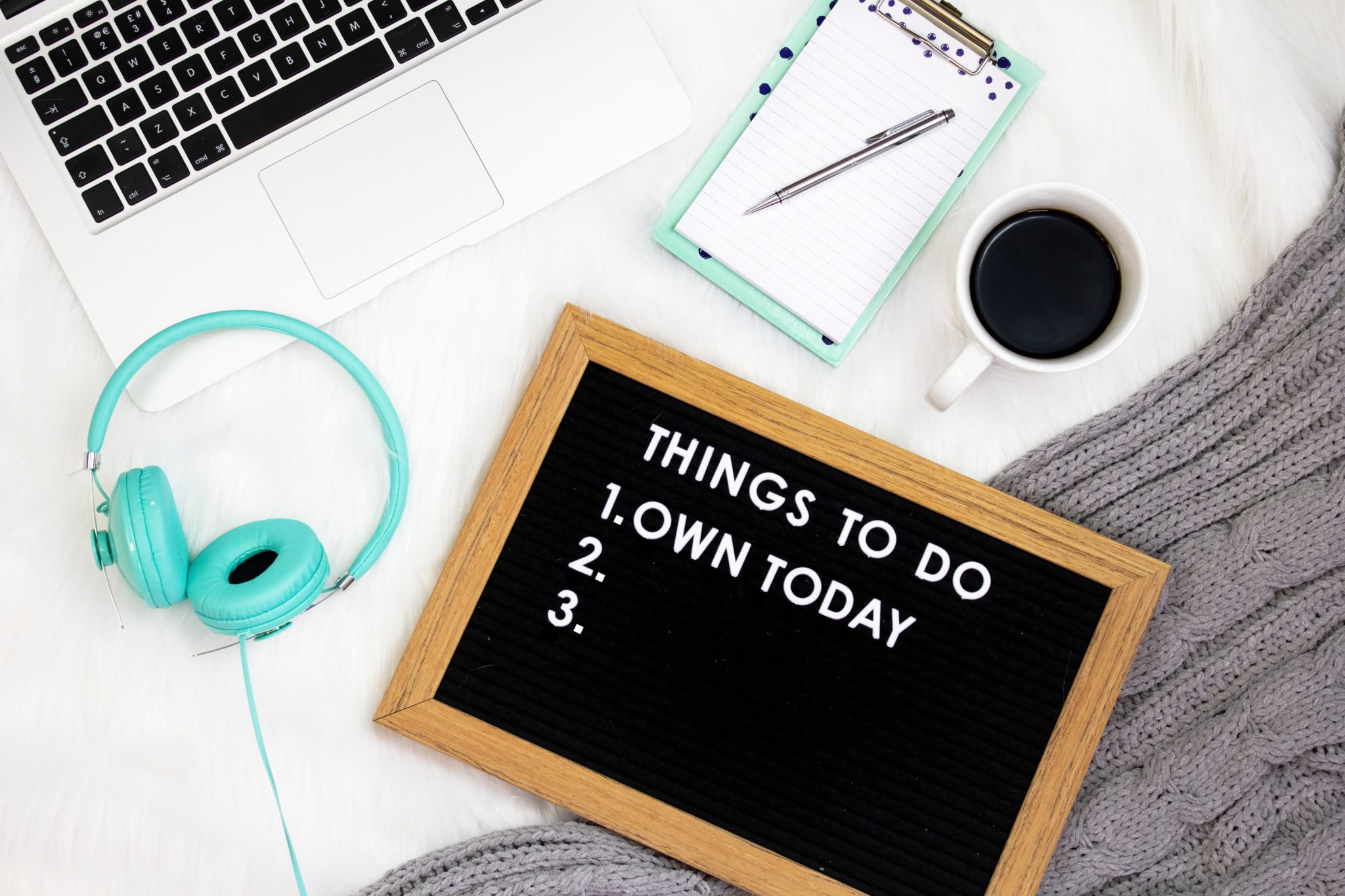 A tablet, headphones, keyboard, & little blackboard with text "Things to do: 1) Own today" with 2 & 3 blank.