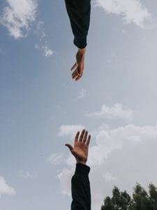 Two hands stretching out toward each other as if to lift each other up by Youssef Naddam on Unsplash