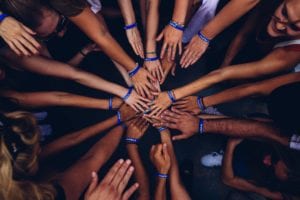 A bunch of people putting their hands on top of one another's as one does when doing team building exercises or getting ready to play sports or a game or something. By Perry Grone on Unsplash