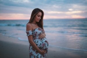 Photo: Woman holding her pregnant belly on the beach at sunset by Neal E. Johnson on Unsplash.