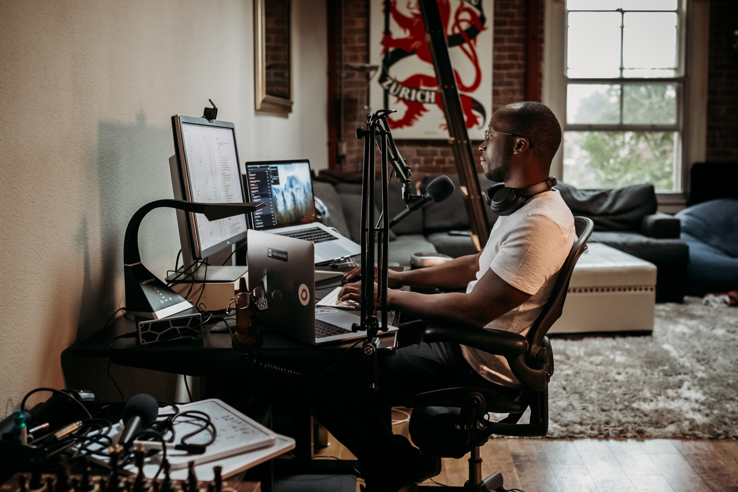 Man sitting at desk with mic and laptops Photo by ConvertKit on Unsplash